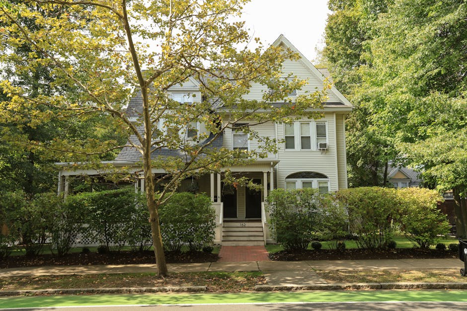 Suburban house with lush front yard greenery and mature landscaping trees